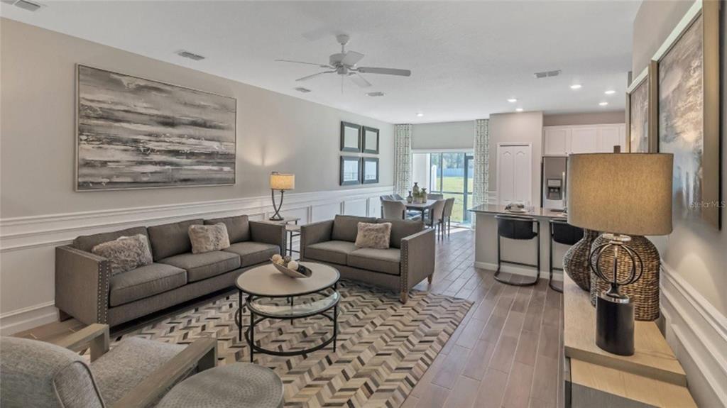 An open-concept living and dining area features gray furniture, tile flooring, and neutral walls — 3488 SE 37TH AVENUE ROAD, OCALA, FL
