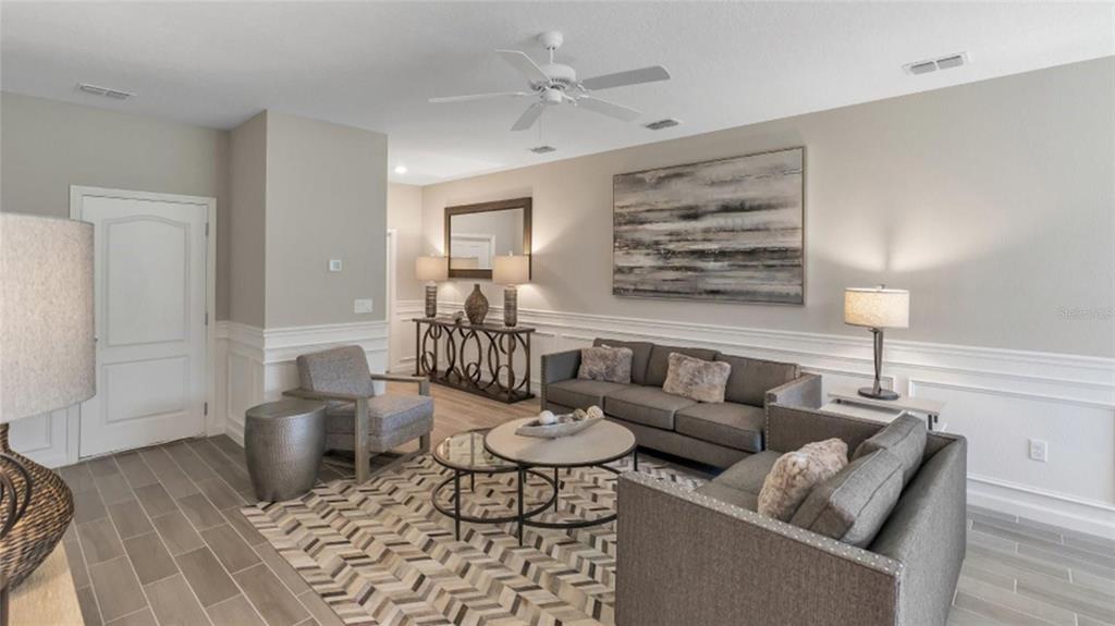 A living room features gray sofas, a patterned rug, and white wainscoting on the walls — 3488 SE 37TH AVENUE ROAD, OCALA, FL
