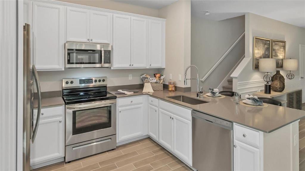 A modern kitchen features white cabinets, stainless steel appliances, and gray countertops — 3488 SE 37TH AVENUE ROAD, OCALA, FL