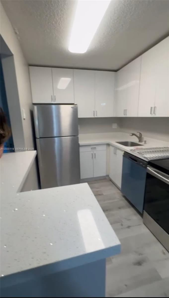 A kitchen features white cabinets, stainless steel appliances, and a white quartz countertop peninsula — 7100 NW 179th St # 102, Hialeah FL 33015, HIALEAH, FL