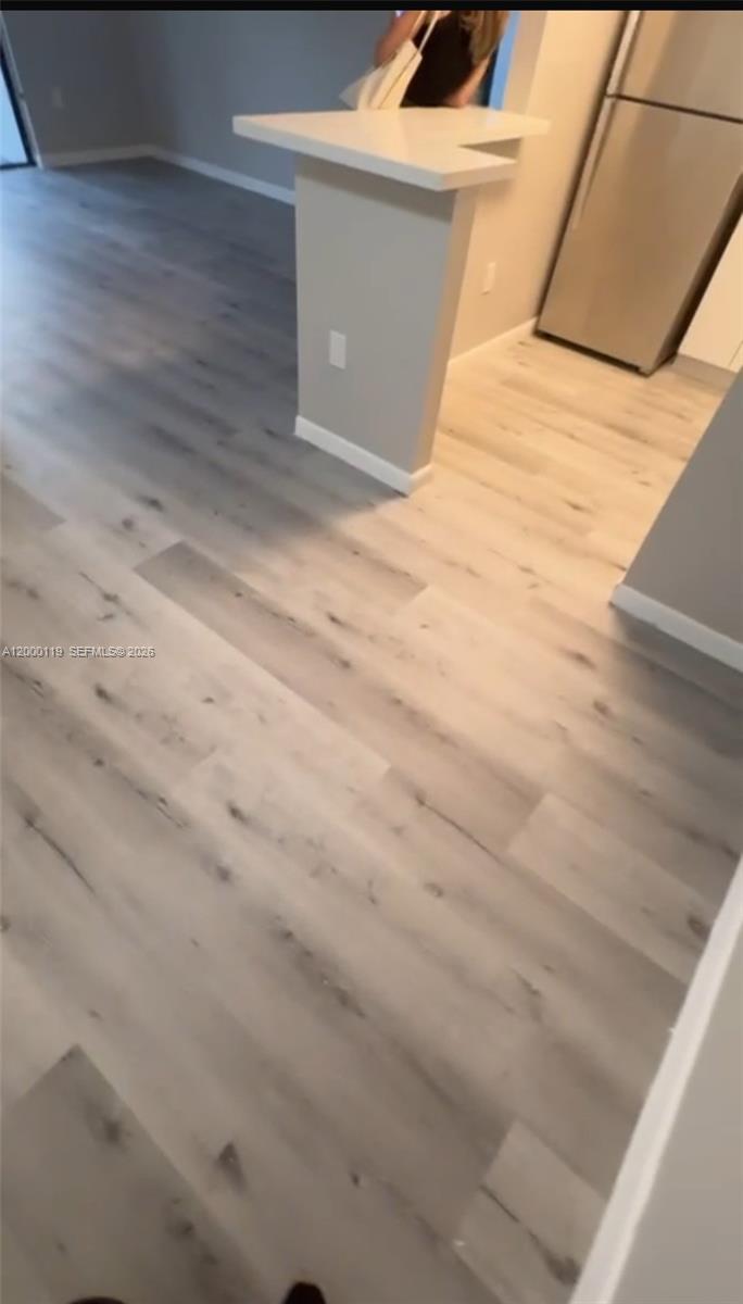 This interior view shows a kitchen with a breakfast bar and light-colored wood-look flooring — 7100 NW 179th St # 102, Hialeah FL 33015, HIALEAH, FL