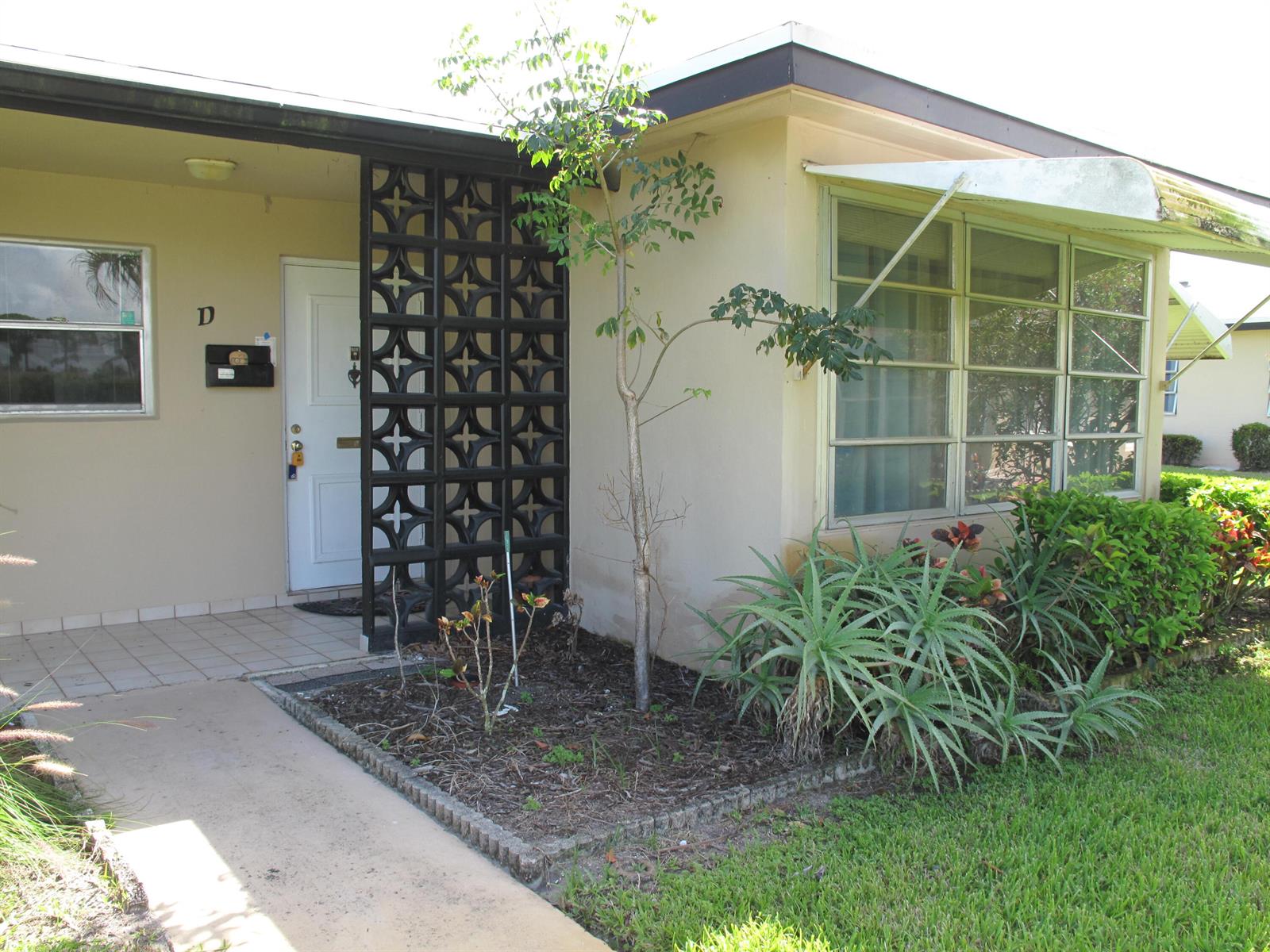 Exterior view of a single-story home with a decorative screen wall and a front walkway — 892 N High Point Boulevard N # D, Delray Beach FL 33445, DELRAY BEACH, FL
