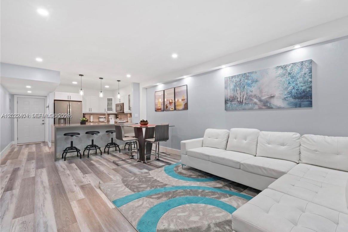 A modern open-concept living room and kitchen featuring a white sectional sofa and island seating — 6125 W 20th Ave # 302, Hialeah FL 33012, HIALEAH, FL