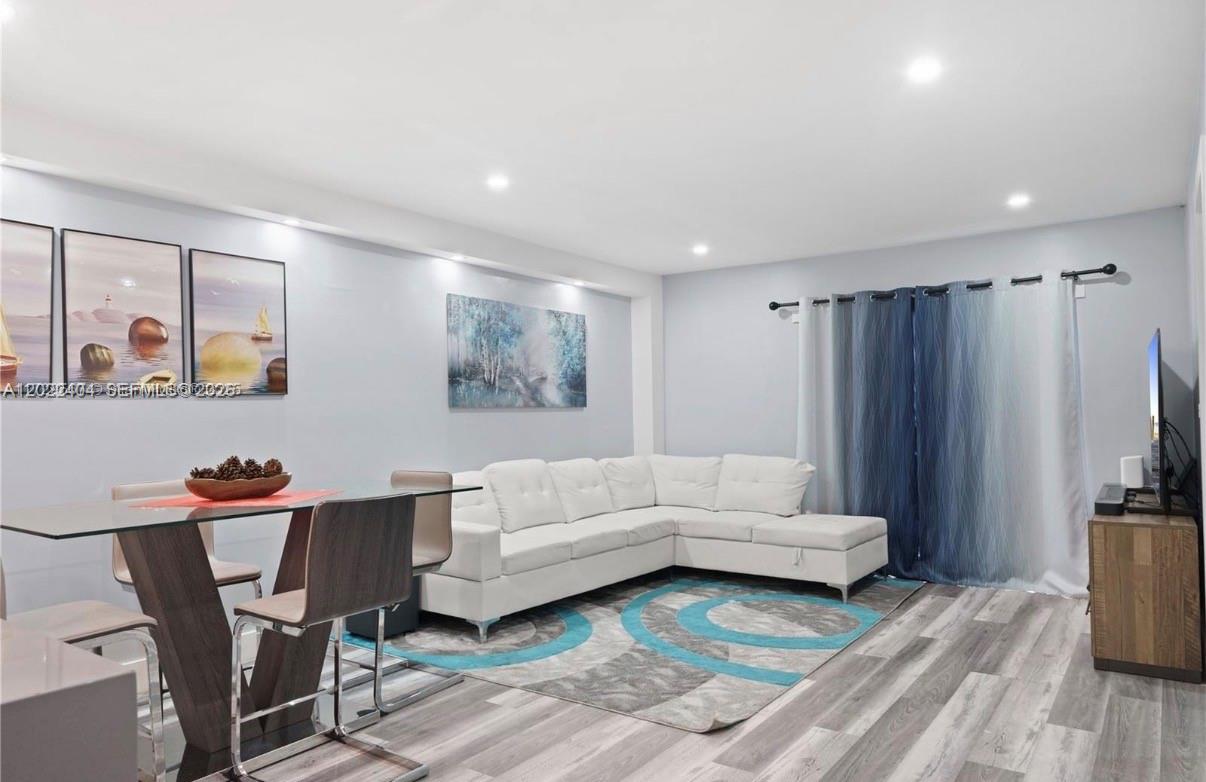 A living and dining area features a white sectional sofa, glass table, and gray flooring — 6125 W 20th Ave # 302, Hialeah FL 33012, HIALEAH, FL