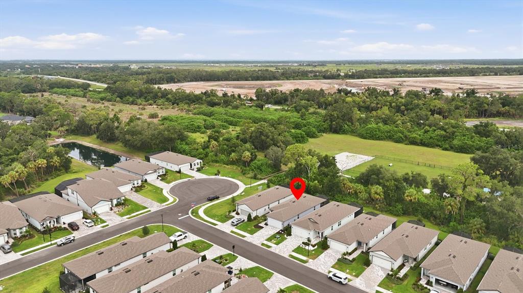 An aerial view shows a residential neighborhood with houses, paved streets, and surrounding green space — 9410 SHOREBIRD COURT, PARRISH, FL