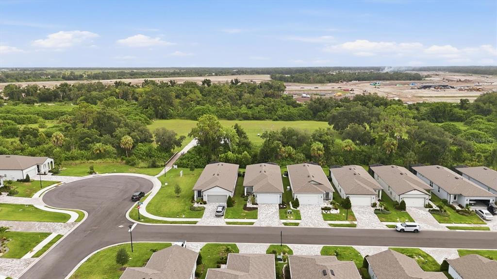 An aerial view shows a suburban street with single-family homes and a nearby construction site — 9410 SHOREBIRD COURT, PARRISH, FL