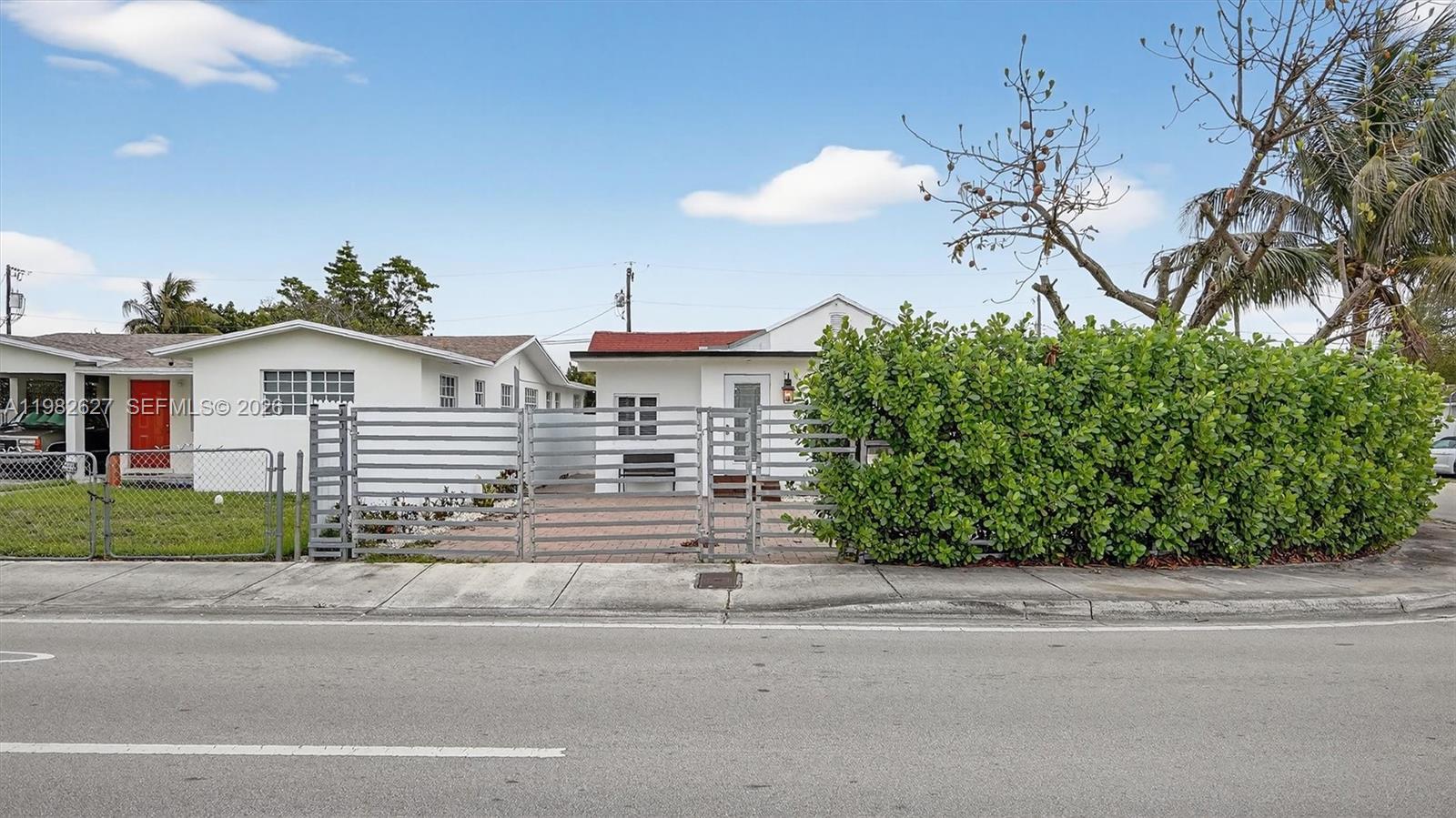 A white house with a red roof sits behind a metal gate and hedge — 2845 SW 67th Ave, Miami FL 33155, MIAMI, FL