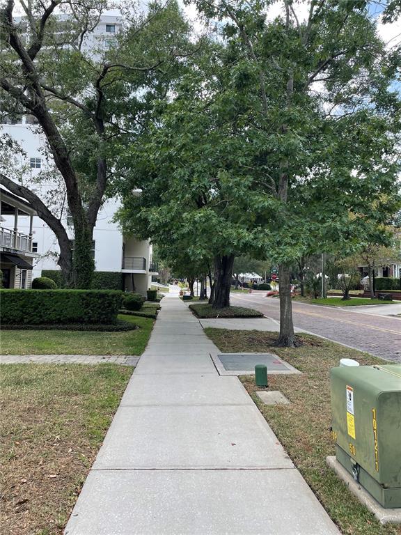 A concrete sidewalk runs between a residential building and a tree-lined brick street — 612 E CENTRAL BOULEVARD, ORLANDO, FL
