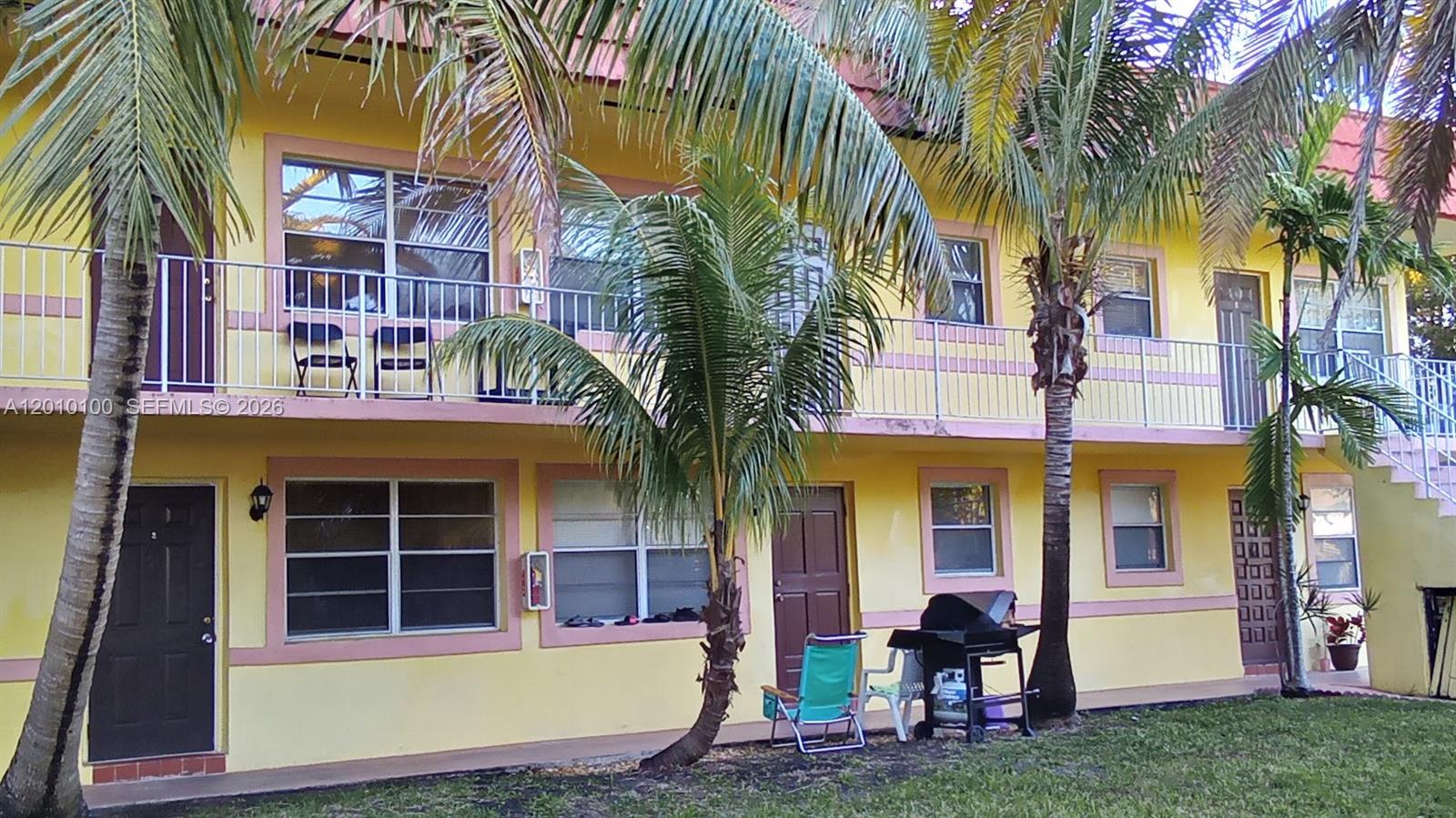 A two-story yellow apartment building features exterior walkways, palm trees, and a grassy yard — 1826 Cleveland St # 3, Hollywood FL 33020, HOLLYWOOD, FL