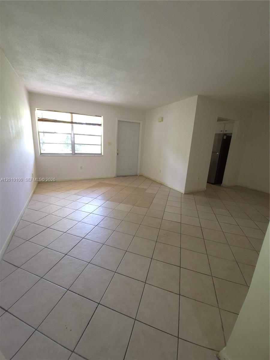 An empty room features light-colored tile flooring, white walls, and a single window — 1826 Cleveland St # 3, Hollywood FL 33020, HOLLYWOOD, FL