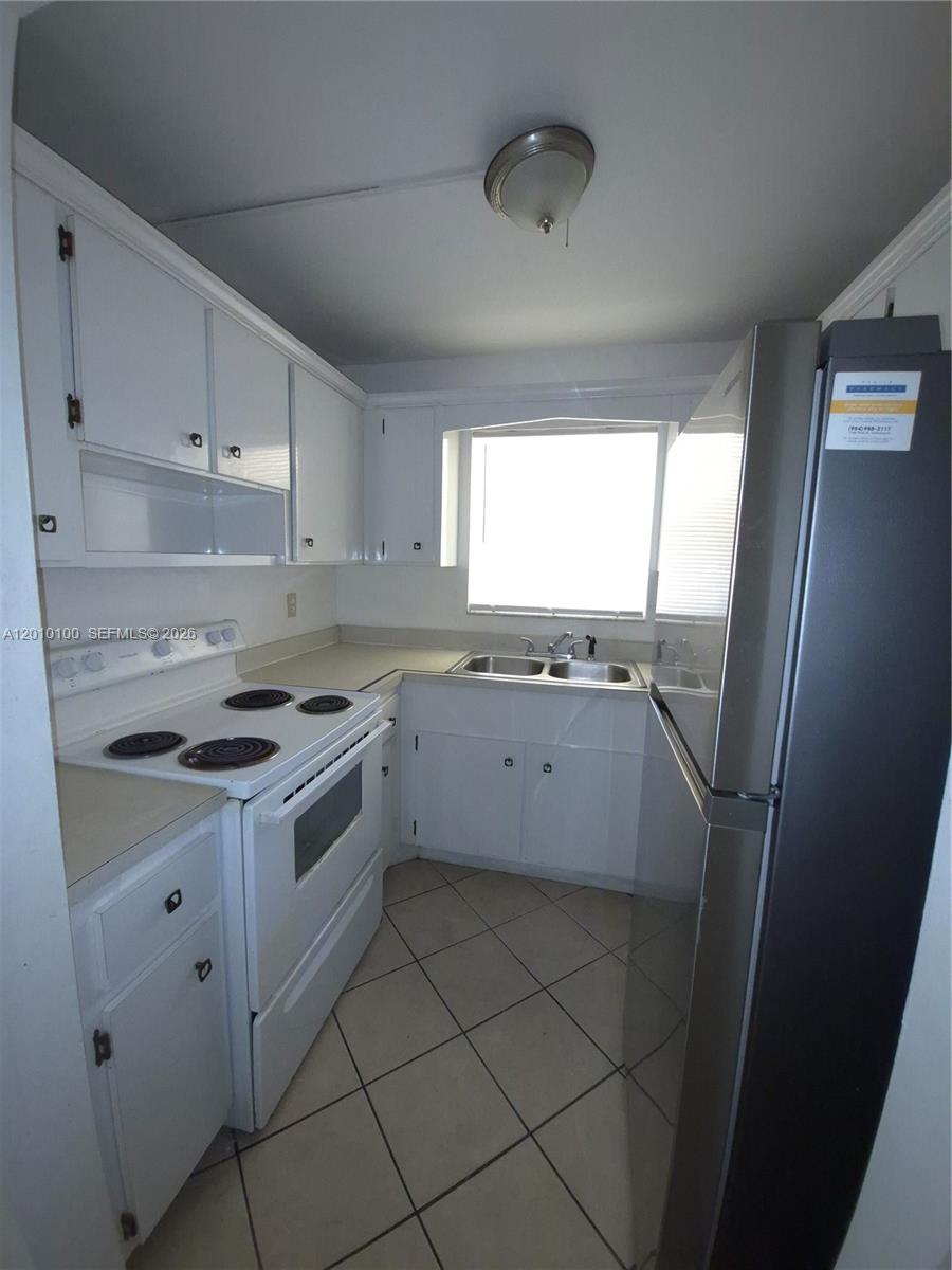 A small kitchen features white cabinets, a white electric stove, and a stainless steel refrigerator — 1826 Cleveland St # 3, Hollywood FL 33020, HOLLYWOOD, FL