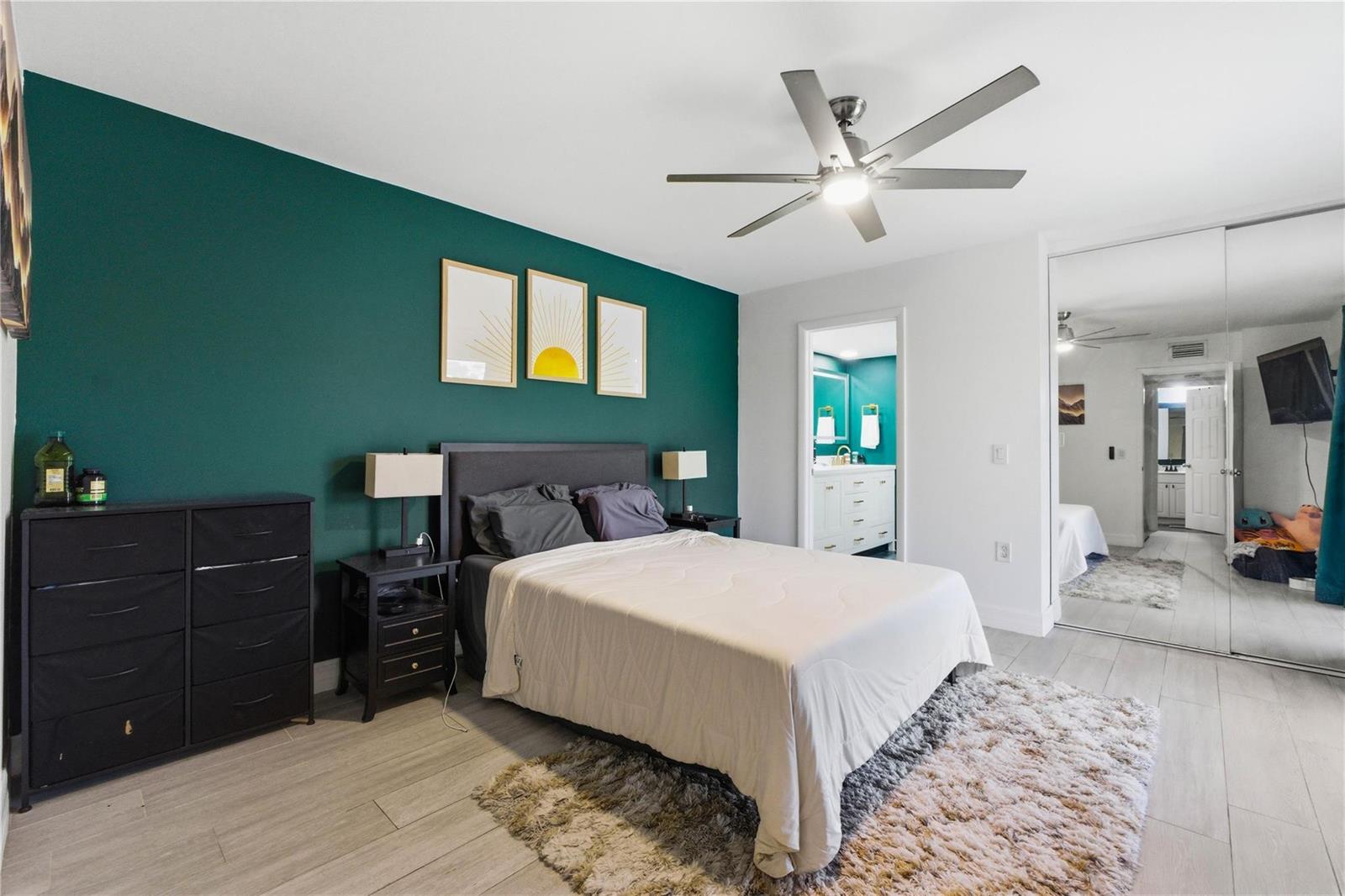 A bedroom features a dark green accent wall, a bed, a dresser, and mirrored closets — 1017 10th Way, West Palm Beach FL 33407, WEST PALM BEACH, FL