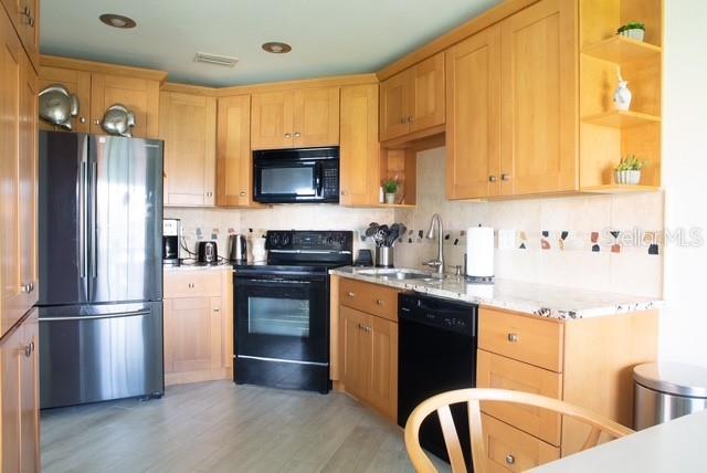 A kitchen features light wood cabinets, stainless steel appliances, and a tiled backsplash — 1515 PINELLAS BAYWAY S UNIT 26, ST PETERSBURG, FL