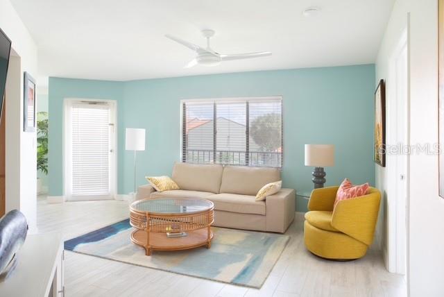 A living room features light blue walls, a beige sofa, a yellow chair, and rug — 1515 PINELLAS BAYWAY S UNIT 26, ST PETERSBURG, FL