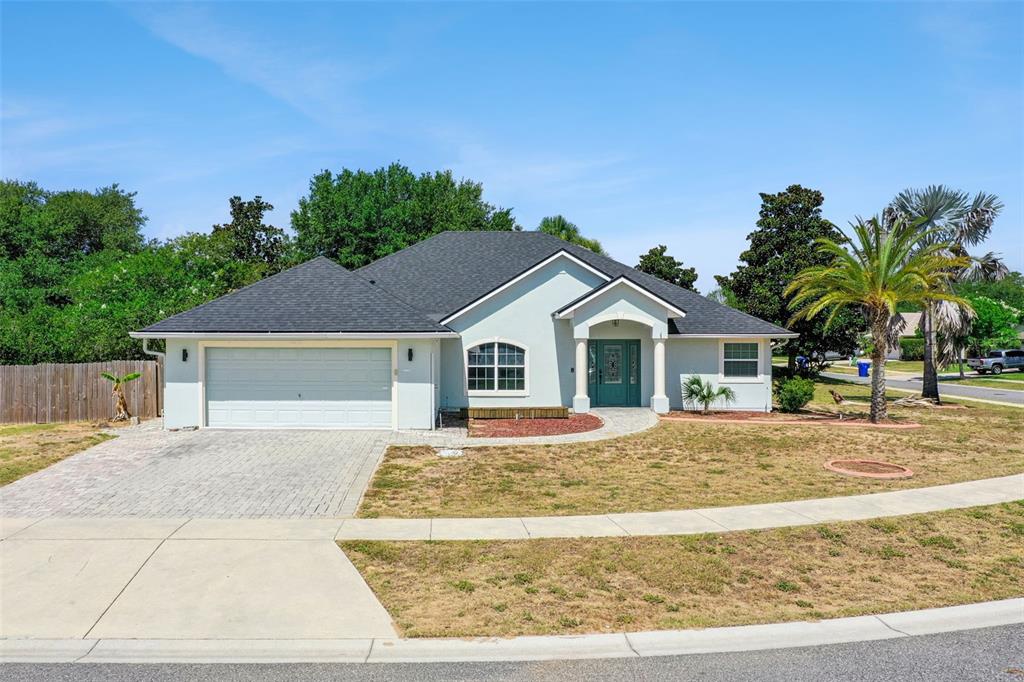 A single-story house with a light-colored stucco exterior, a two-car garage, and a palm tree — 4450 ABACO DRIVE, TAVARES, FL