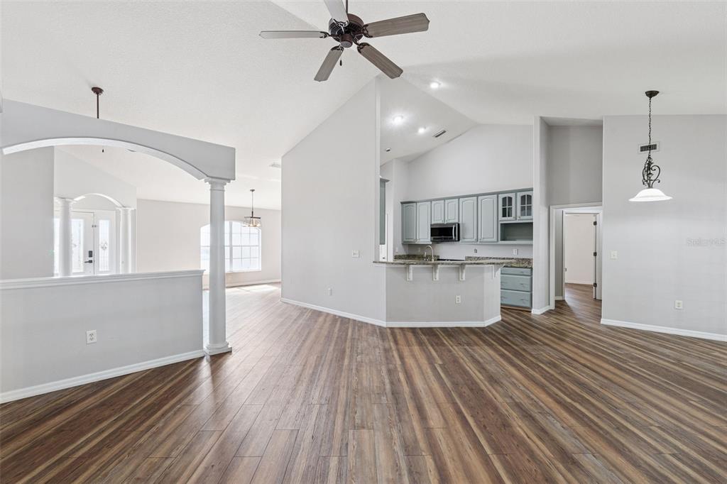 An open-concept living area with wood-look flooring, a vaulted ceiling, and a kitchen with cabinets — 4450 ABACO DRIVE, TAVARES, FL