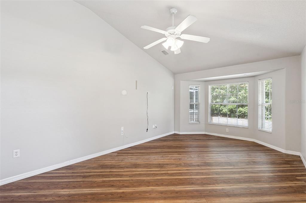 An empty living room features light gray walls, wood-look flooring, a ceiling fan, and windows — 4450 ABACO DRIVE, TAVARES, FL