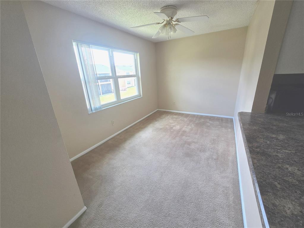 This carpeted dining area features a ceiling fan, a window with blinds, and beige walls — 9933 SWEEPSTAKES LANE UNIT 4, ORLANDO, FL