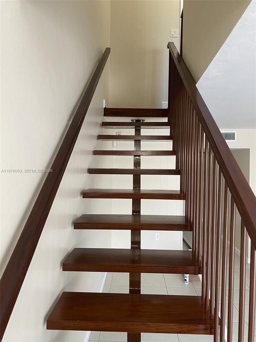 A staircase with dark wood treads and a central support beam ascends between two railings — 2183 NE 122nd St # 2183, North Miami FL 33181, NORTH MIAMI, FL