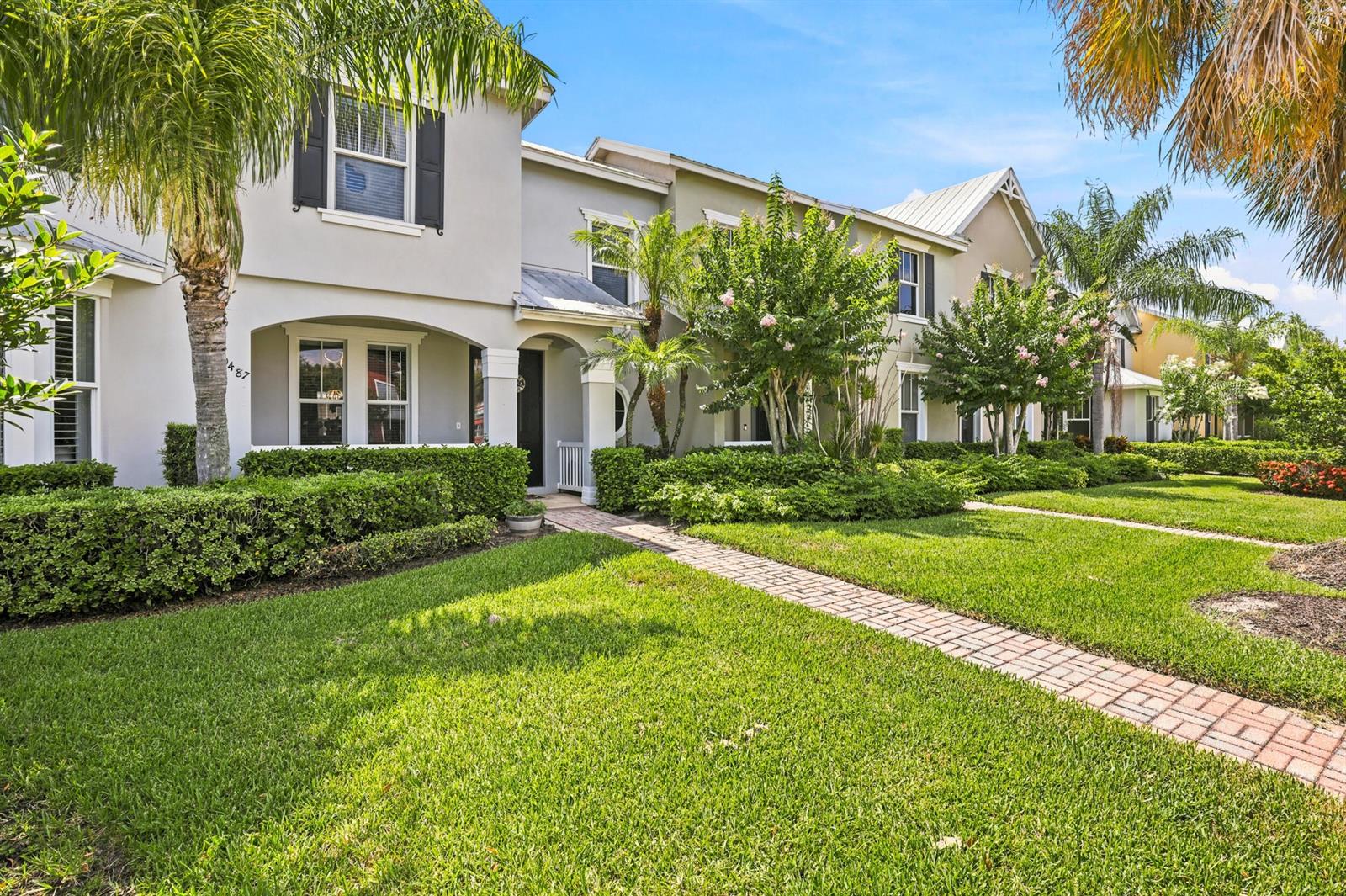 A two-story townhouse exterior features a brick walkway, manicured hedges, and palm trees — 10487 SW West Park Avenue, FL 34987, FL