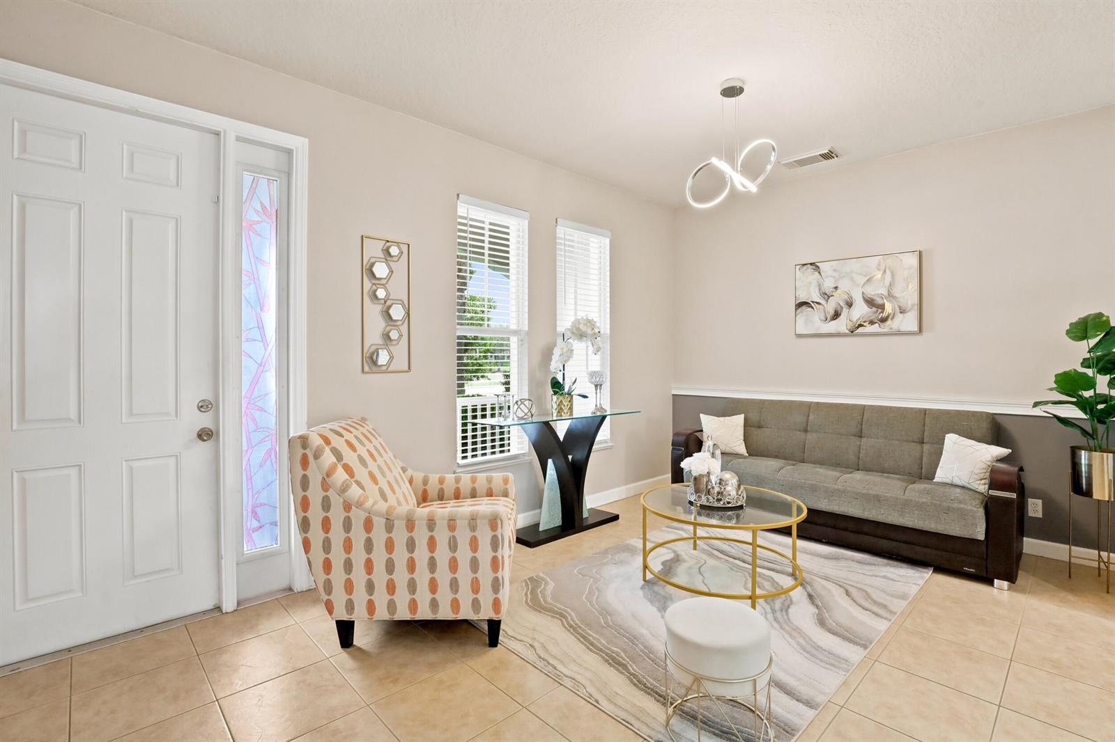 A living room features a patterned armchair, a grey sofa, and a glass coffee table — 10487 SW West Park Avenue, FL 34987, FL