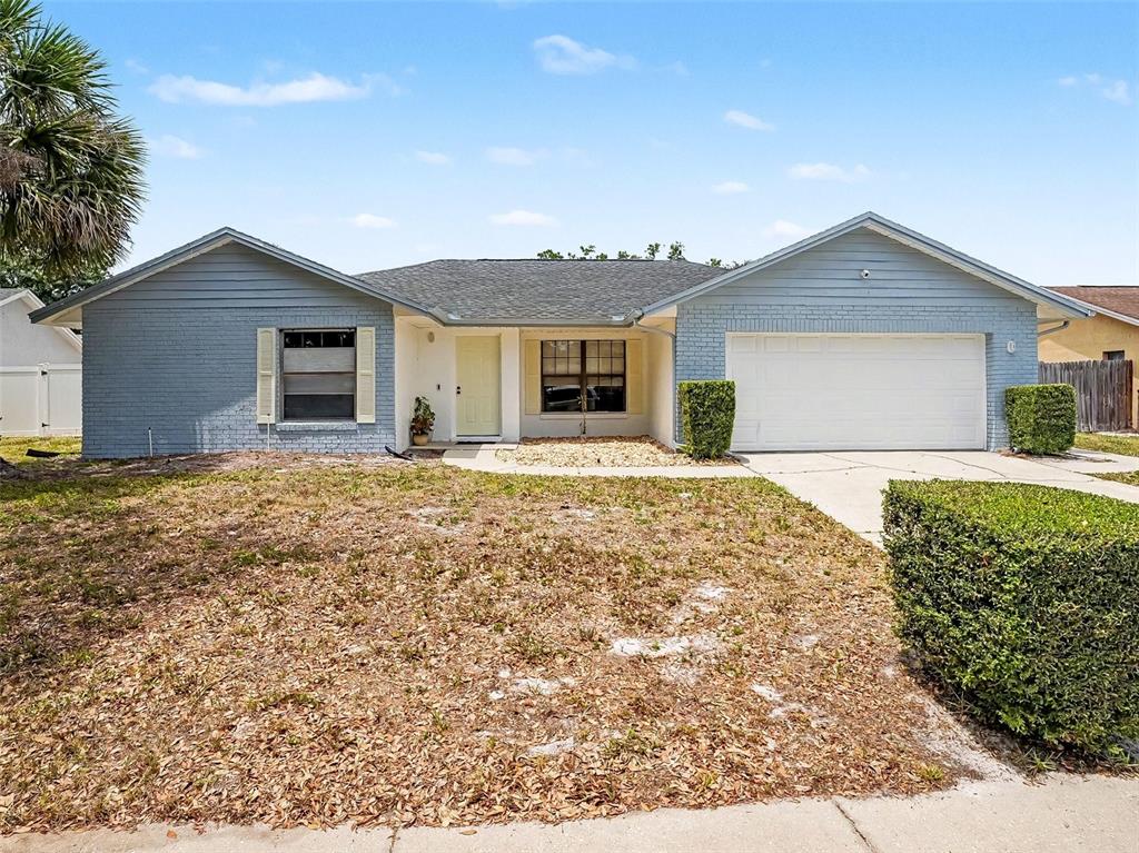 A single-story house with blue brick siding, a two-car garage, and a front lawn — 1006 WHEELER PLACE, OVIEDO, FL
