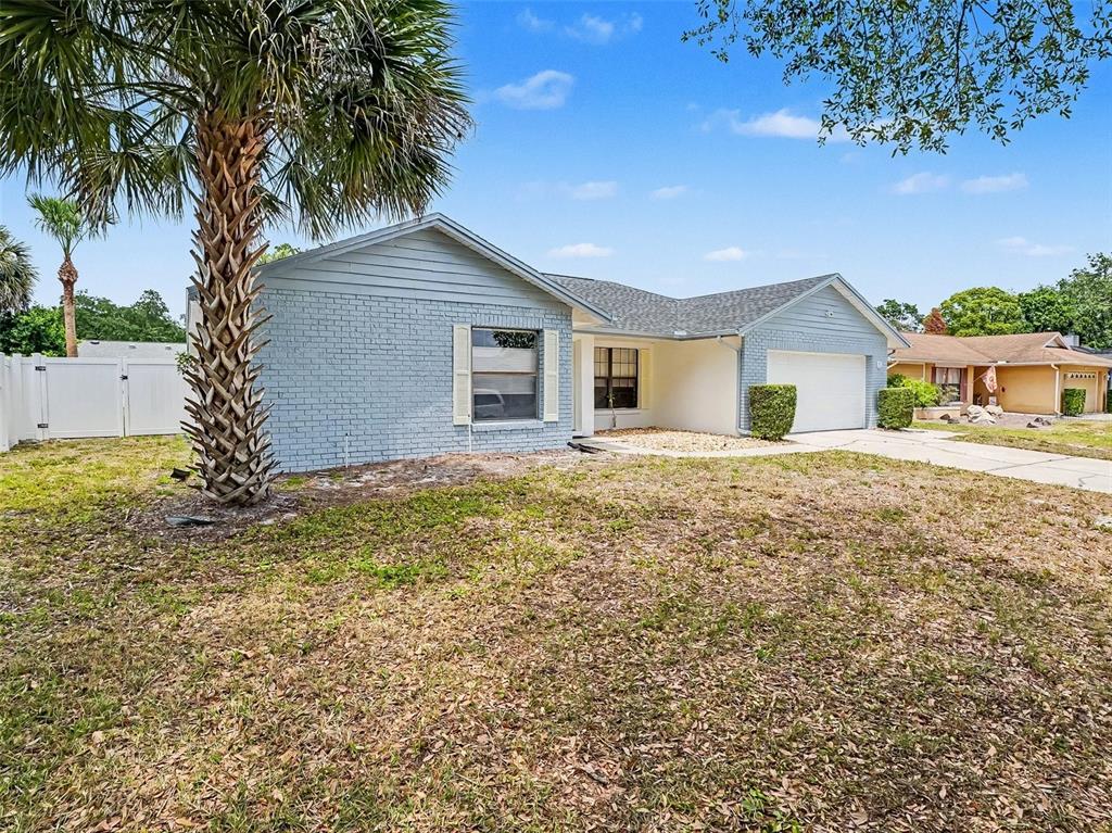A light blue, single-story brick house with a palm tree and a front-facing garage — 1006 WHEELER PLACE, OVIEDO, FL