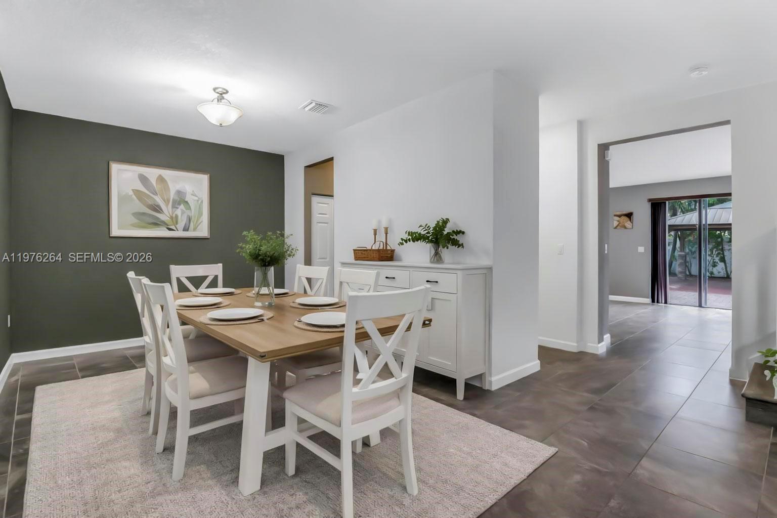 A dining room features a wooden table, white chairs, and a dark accent wall — 3440 W 100th Ter, Hialeah FL 33018, HIALEAH, FL