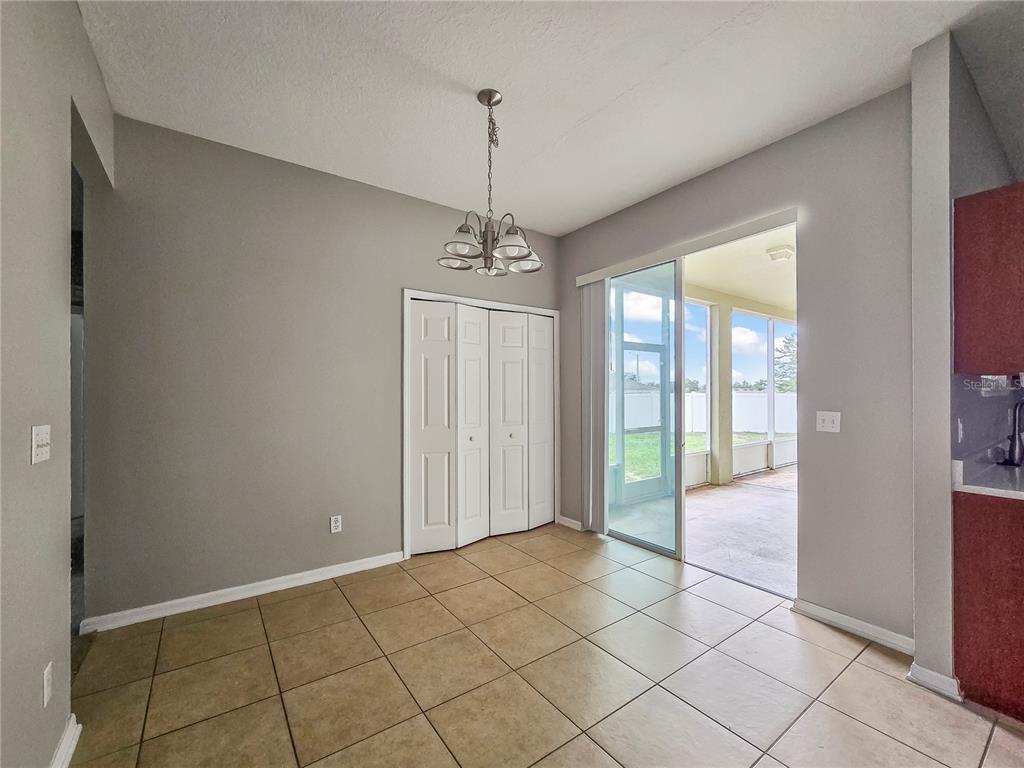 A dining area with tile flooring, a chandelier, a bi-fold closet, and a sliding glass door — 1801 HOOFPRINT COURT, FRUITLAND PARK, FL