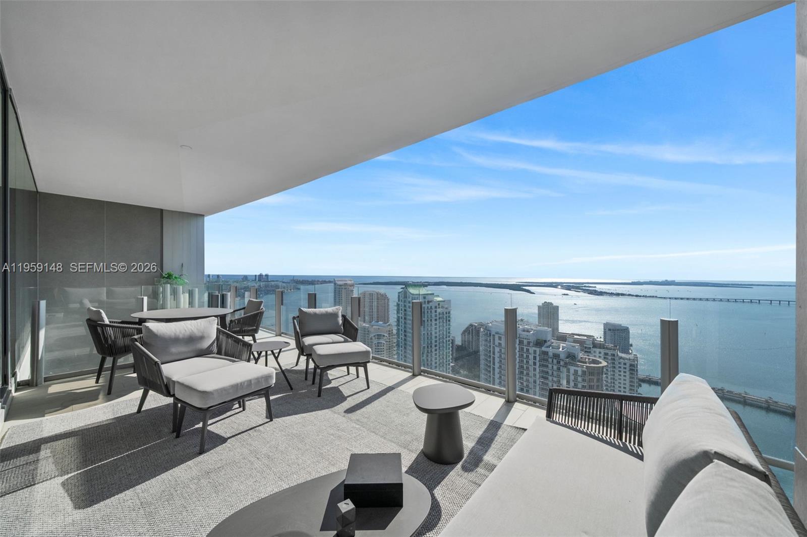 A high-rise balcony features outdoor lounge furniture overlooking a bay and city skyline — 300 Biscayne Blvd Way # 4602, Miami FL 33131, MIAMI, FL