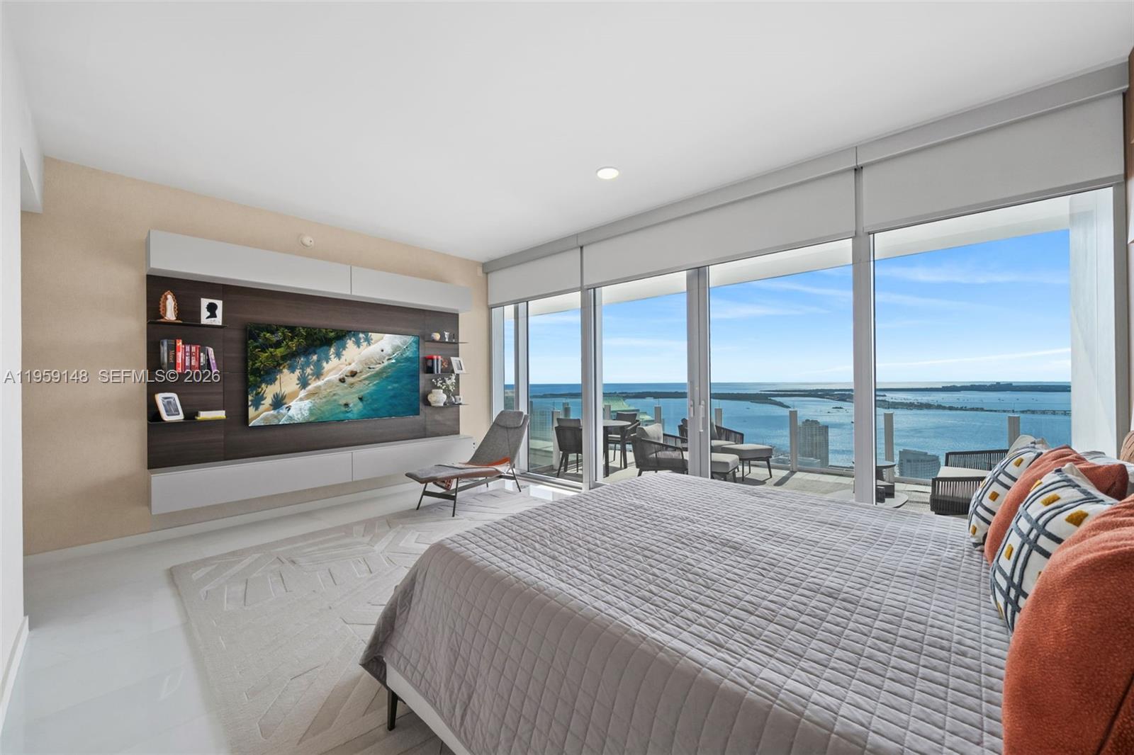 A modern bedroom features a wall-mounted television, a gray bed, and floor-to-ceiling windows overlooking water — 300 Biscayne Blvd Way # 4602, Miami FL 33131, MIAMI, FL