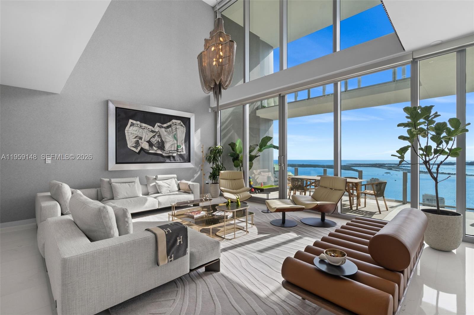 A modern living room features floor-to-ceiling windows with ocean views and a large chandelier — 300 Biscayne Blvd Way # 4602, Miami FL 33131, MIAMI, FL