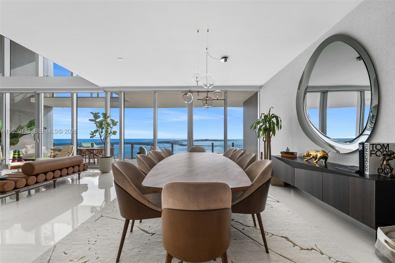 A dining room features an oval table, upholstered chairs, a large mirror, and ocean views — 300 Biscayne Blvd Way # 4602, Miami FL 33131, MIAMI, FL