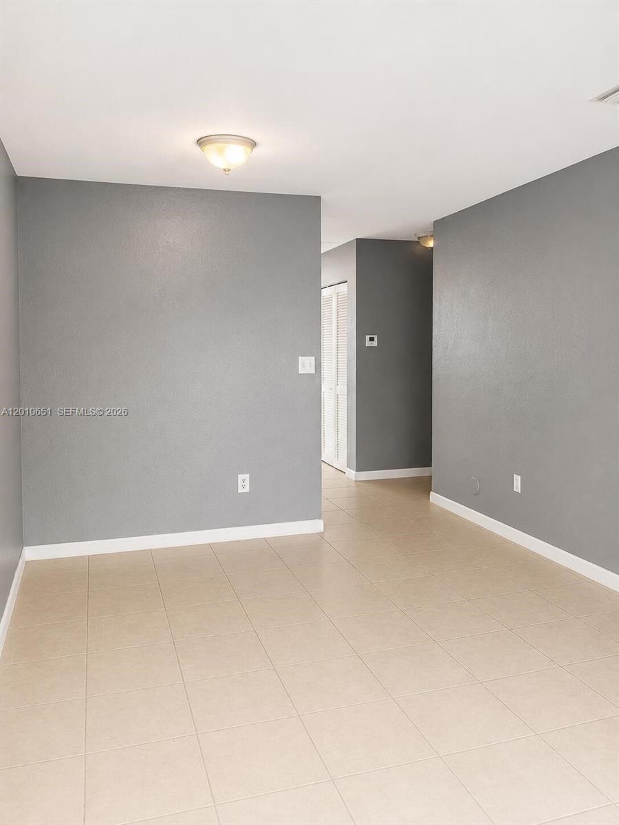 An empty room features gray walls, light-colored tile flooring, and a ceiling-mounted light fixture — 8180 NW 23rd Ave # A, Miami FL 33147, MIAMI, FL