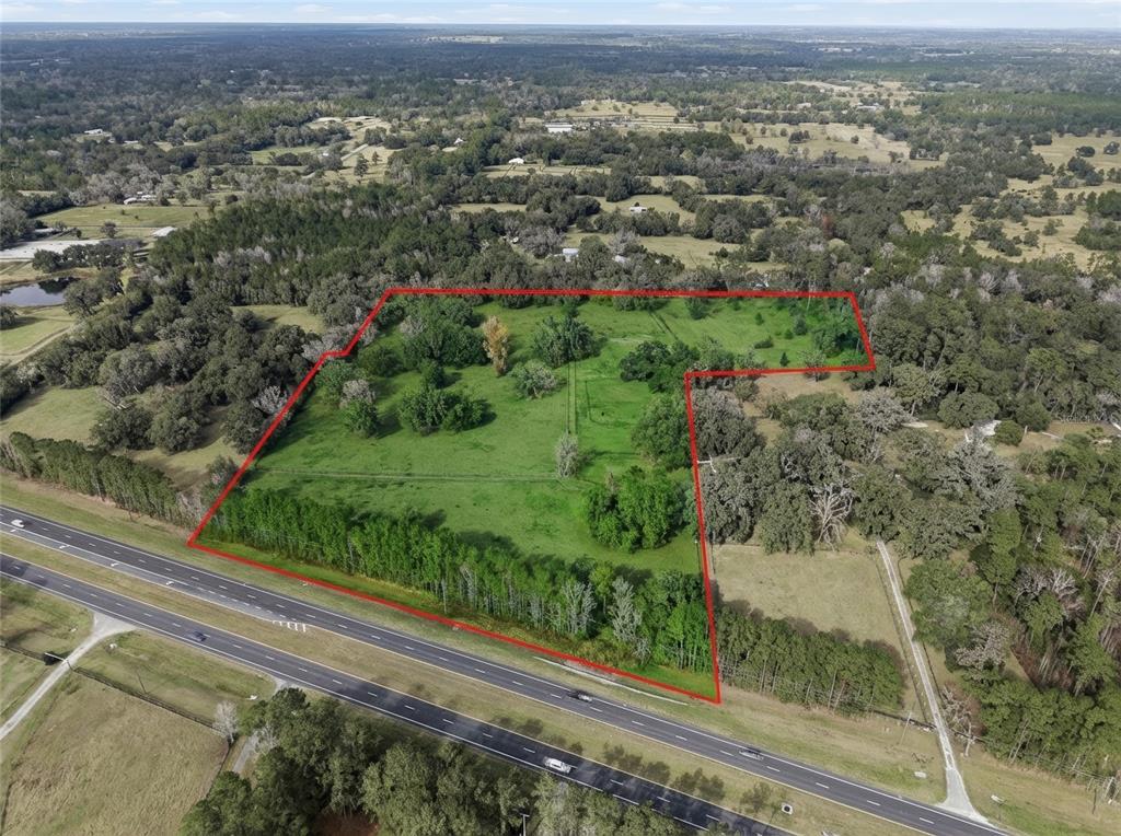 An aerial view shows a large, grassy, tree-lined lot bordered by a multi-lane highway — 0 N HWY US 27, OCALA, FL
