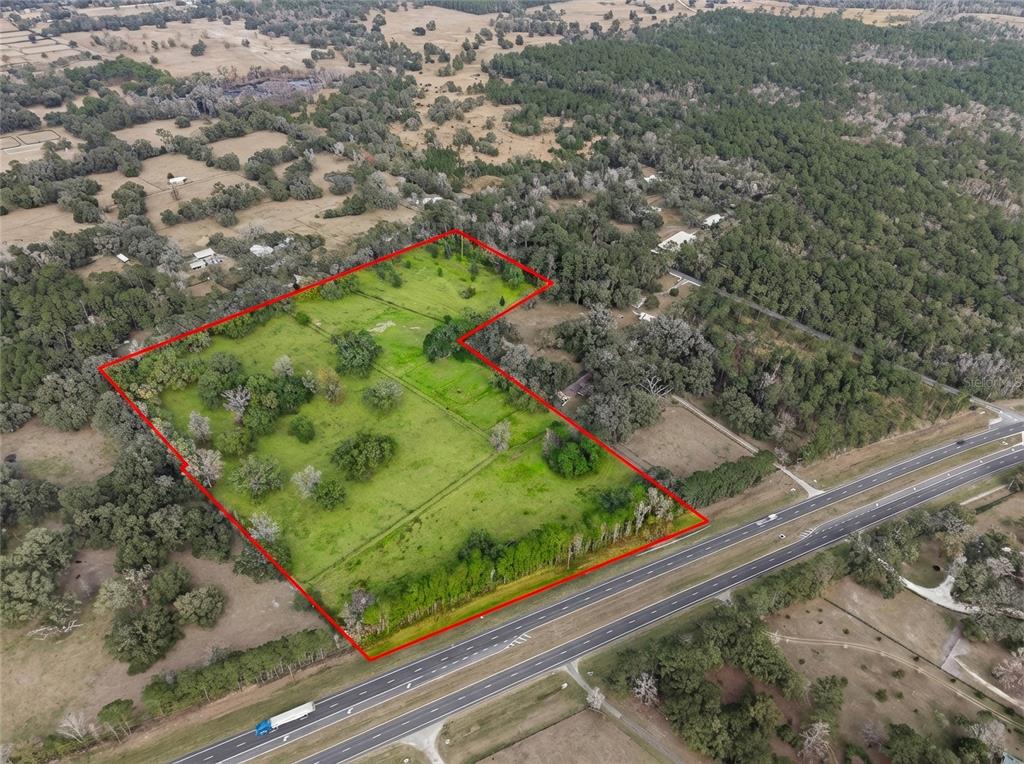 An aerial view shows a large, grassy, fenced plot of land bordering a multi-lane highway — 0 N HWY US 27, OCALA, FL