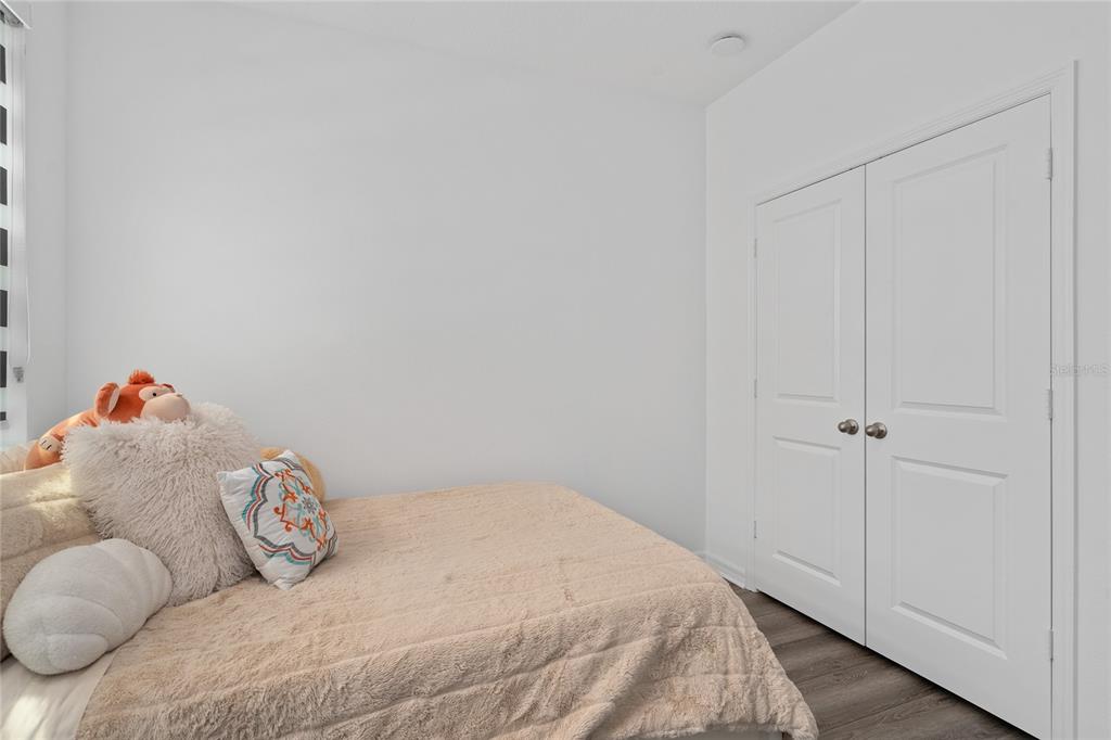 A bedroom features a bed with plush pillows, white walls, and a double-door closet — 655 CLARK STREET, OVIEDO, FL