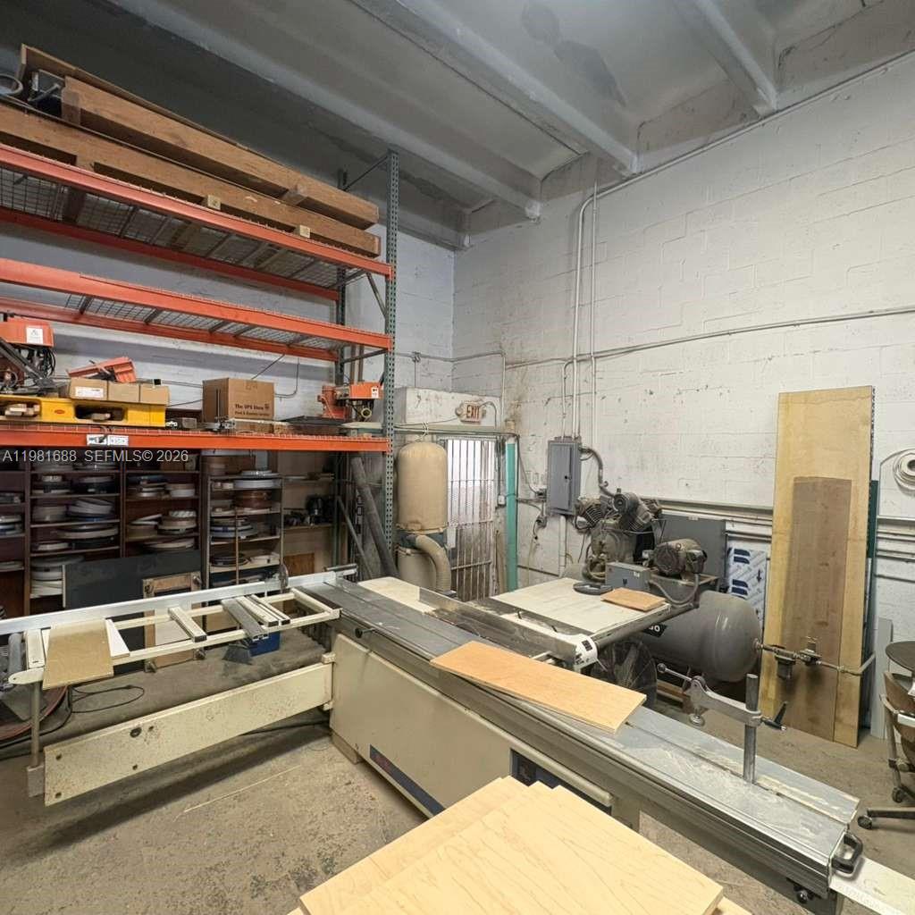 A workshop space features a large sliding table saw, industrial shelving, and exposed brick walls — 2683 76, Hialeah FL 33016, HIALEAH, FL