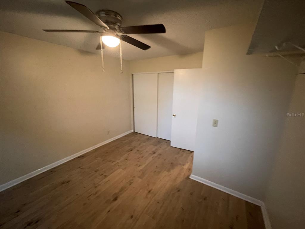 A bedroom with light-colored walls, wood-look flooring, a ceiling fan, and a sliding closet door — 230 MILLARD AVENUE UNIT 1, LAKELAND, FL