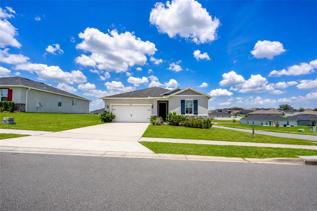 A single-story suburban house with a two-car garage and a concrete driveway — 3349 PINK OLEANDER AVENUE, MASCOTTE, FL