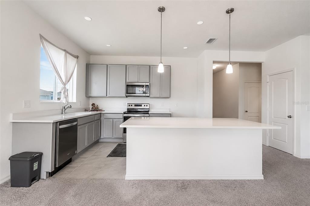A kitchen featuring gray cabinets, white countertops, a center island, and stainless steel appliances — 3349 PINK OLEANDER AVENUE, MASCOTTE, FL