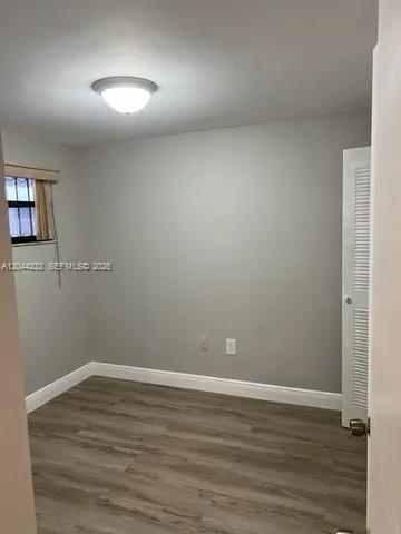An empty bedroom features light gray walls, wood-look flooring, a window, and a louvered closet door — 777 SW 9th Ave # 414, Miami FL 33130, MIAMI, FL