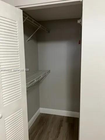 A small walk-in closet features white louvered doors, wire shelving, and wood-look flooring — 777 SW 9th Ave # 414, Miami FL 33130, MIAMI, FL