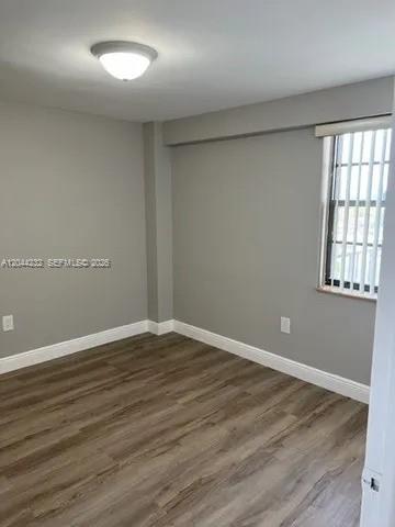 An empty room with gray walls, wood-look flooring, a ceiling light, and a window — 777 SW 9th Ave # 414, Miami FL 33130, MIAMI, FL