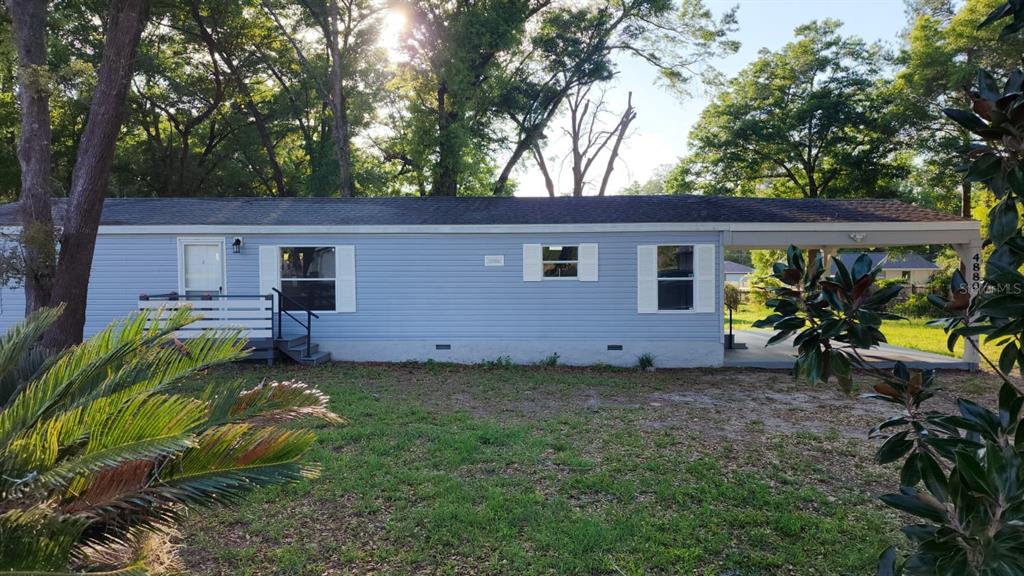 A light blue single-wide mobile home with a front porch and an attached carport — 4880 NW 60TH TERRACE, OCALA, FL
