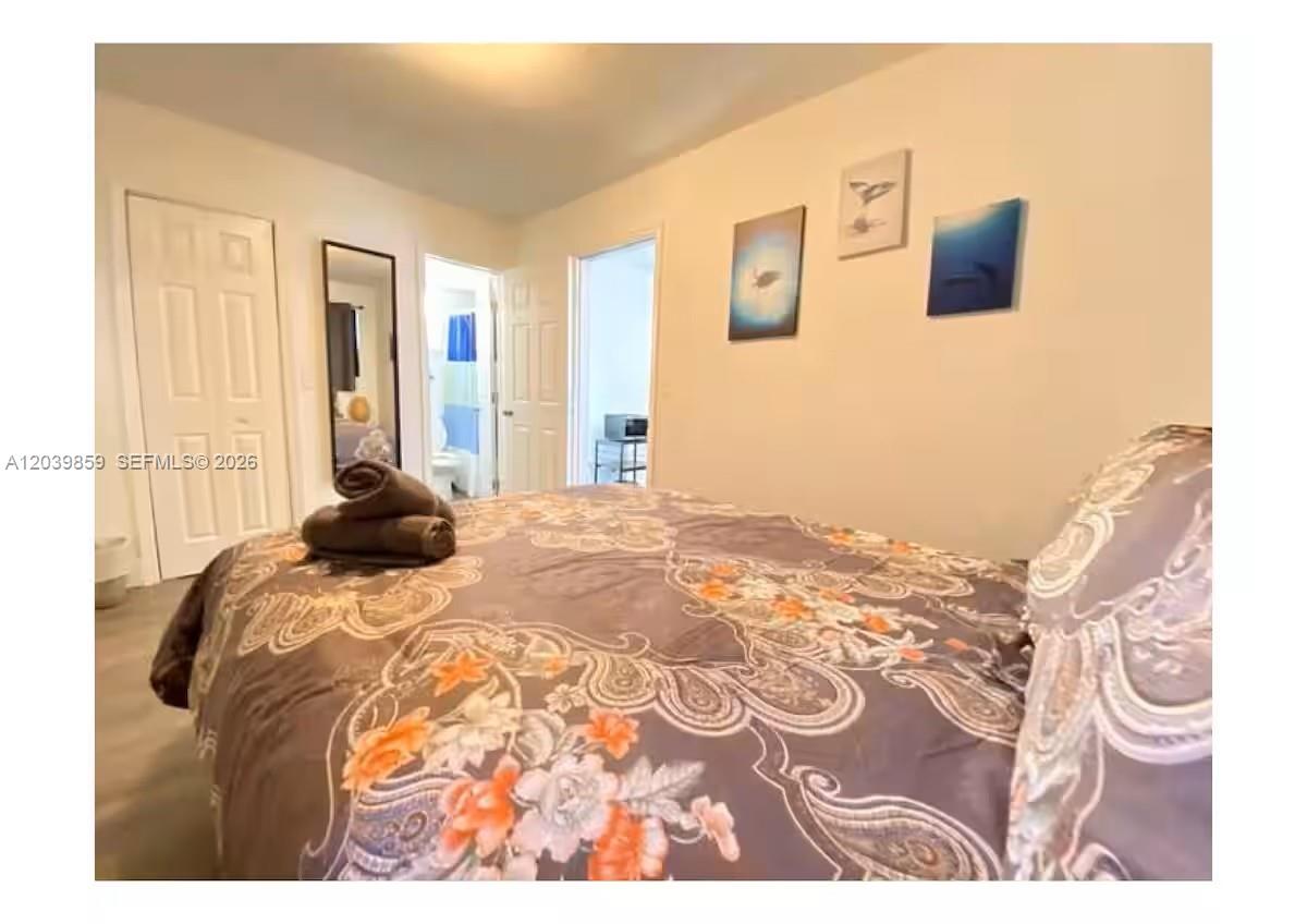 A bedroom features a bed with a patterned comforter, two doors, and wall art — 7638 N Miami Ave # 2, Miami FL 33150, MIAMI, FL