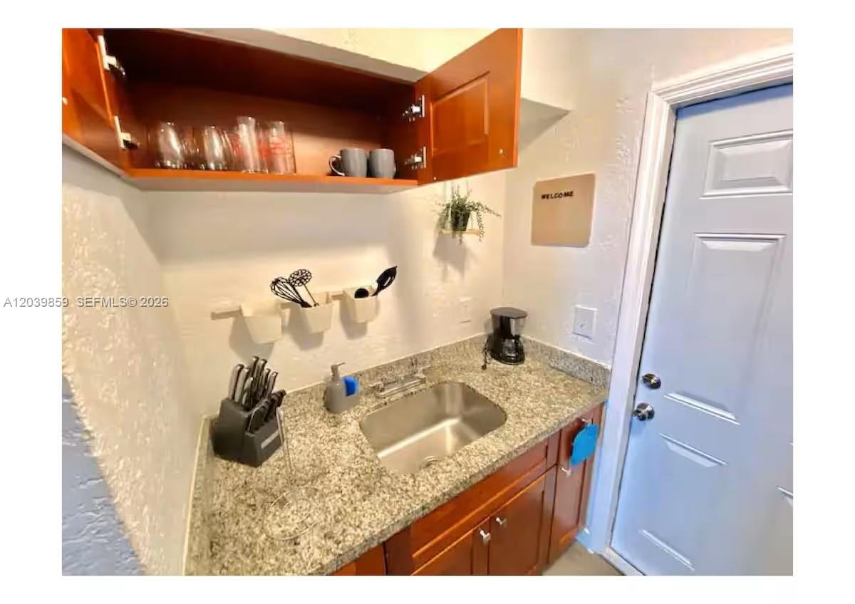 A small kitchenette features granite countertops, a stainless steel sink, and wooden cabinets — 7638 N Miami Ave # 2, Miami FL 33150, MIAMI, FL