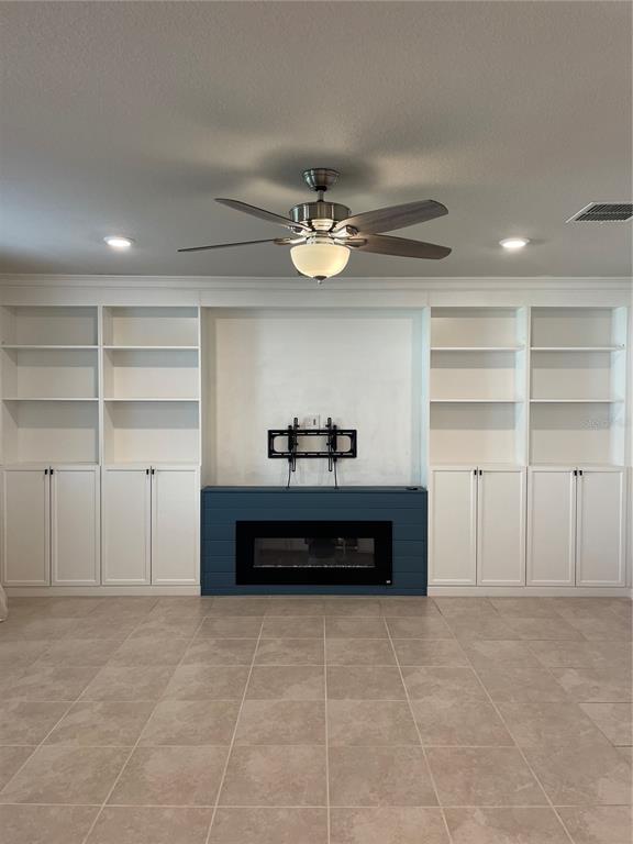 A living room features a blue fireplace, a wall-mounted TV bracket, and built-in white shelving — 5503 KEATON SPRINGS DRIVE, LAKELAND, FL