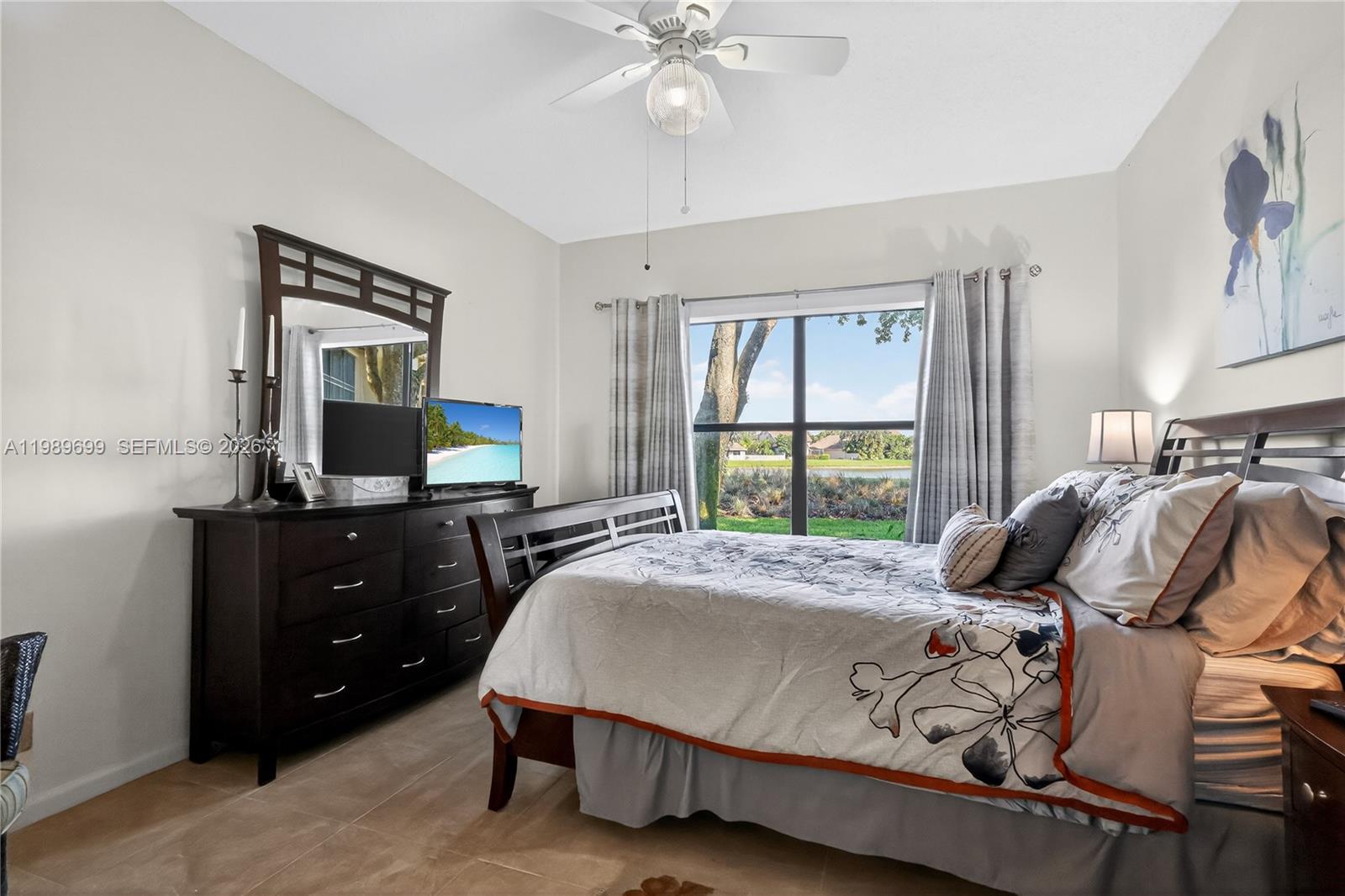 A bedroom features a dark wood bed frame, a matching dresser with a mirror, and windows — 8033 Aberdeen Dr # 102, Boynton Beach FL 33472, BOYNTON BEACH, FL