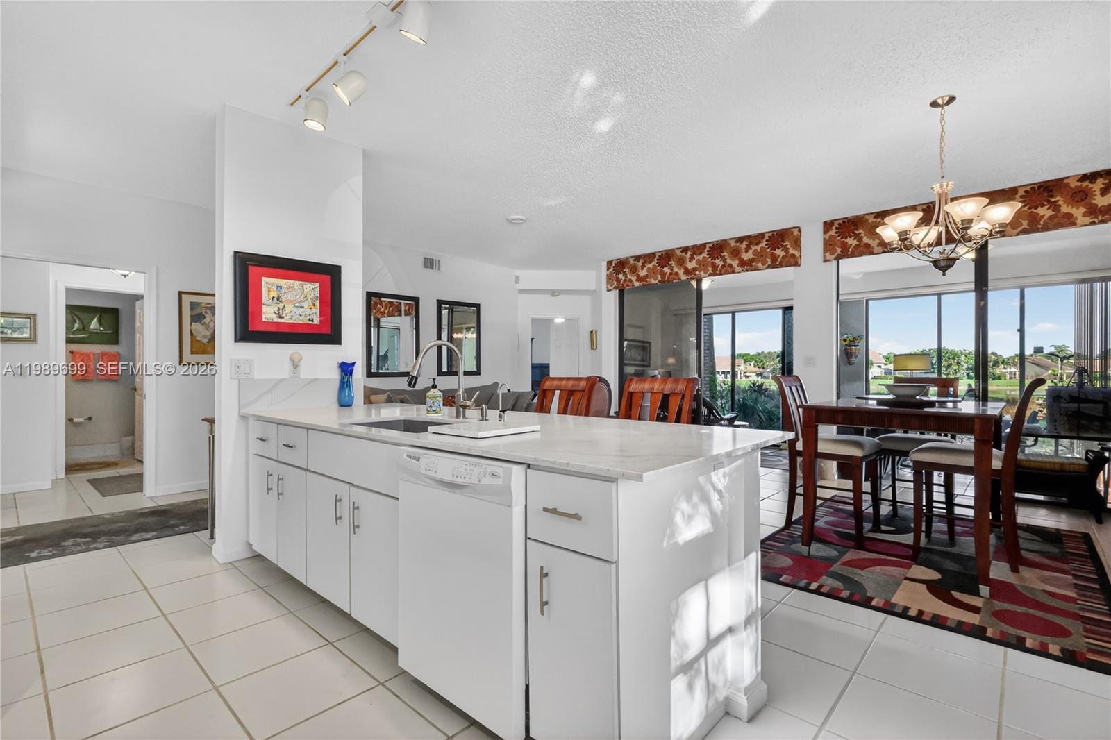 A kitchen island with a white countertop and dishwasher sits before a dining area — 8033 Aberdeen Dr # 102, Boynton Beach FL 33472, BOYNTON BEACH, FL